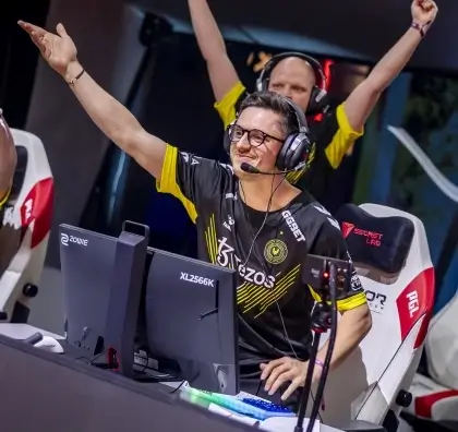 Esports player in black and yellow jersey cheering during gaming competition.