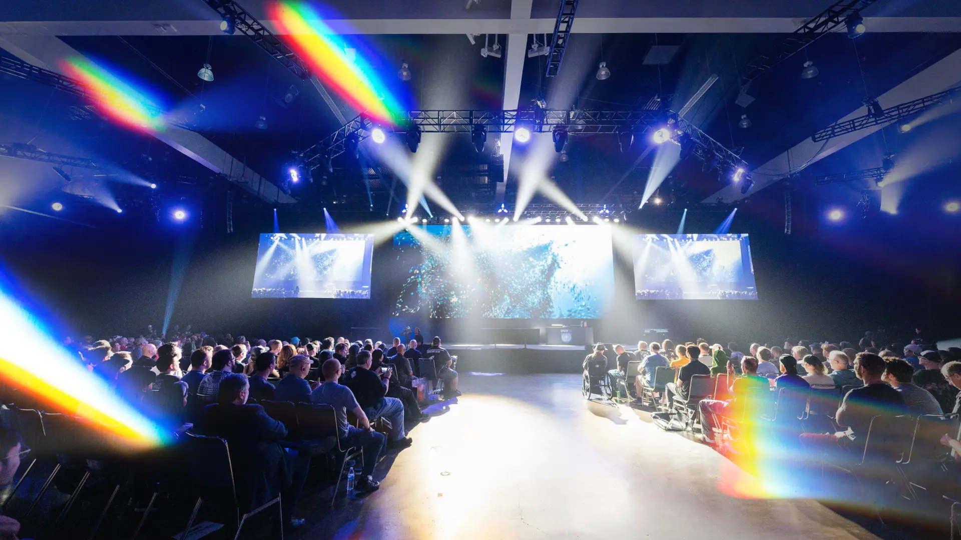 Large esports and gaming business conference with a full audience facing a main stage and multiple screens, representing major esports industry events in 2026.