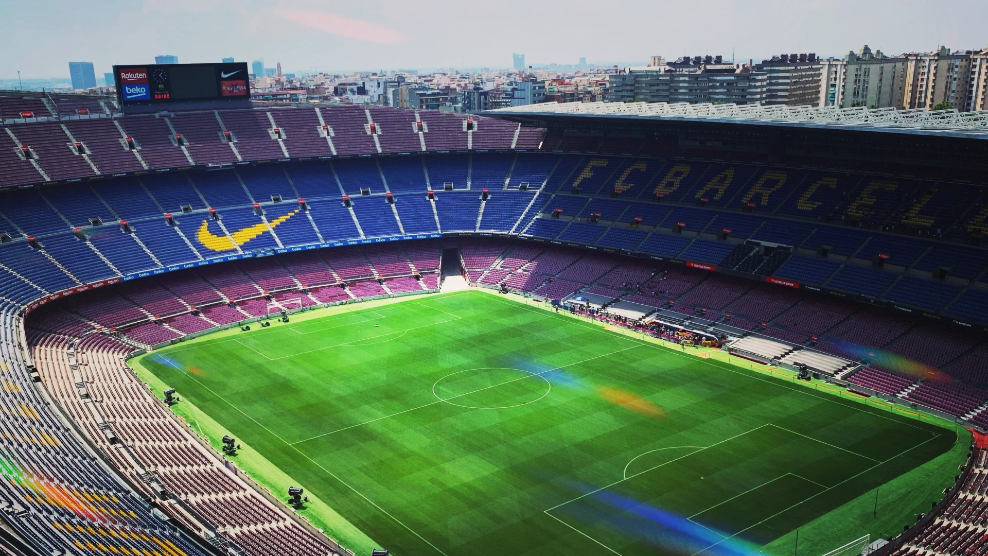 A wide-angle view of an empty football stadium with vibrant green turf and rows of red and blue seats forming the letters “FCB.” Prominent brand logos are visible on the stands, highlighting the commercial presence in professional sports. The image illustrates the scale and visibility that make football sponsorship deals so valuable for global brands seeking exposure and fan engagement.