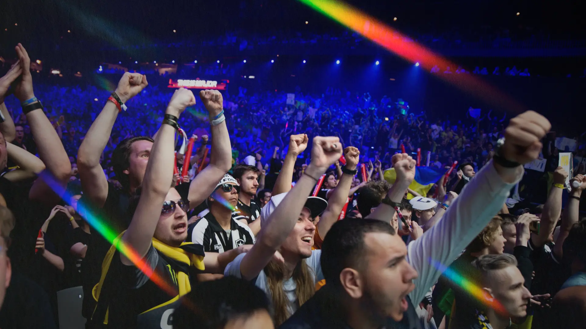 Esports team celebrating championship victory with trophy amid golden confetti and rainbow lighting effects at professional gaming tournament
